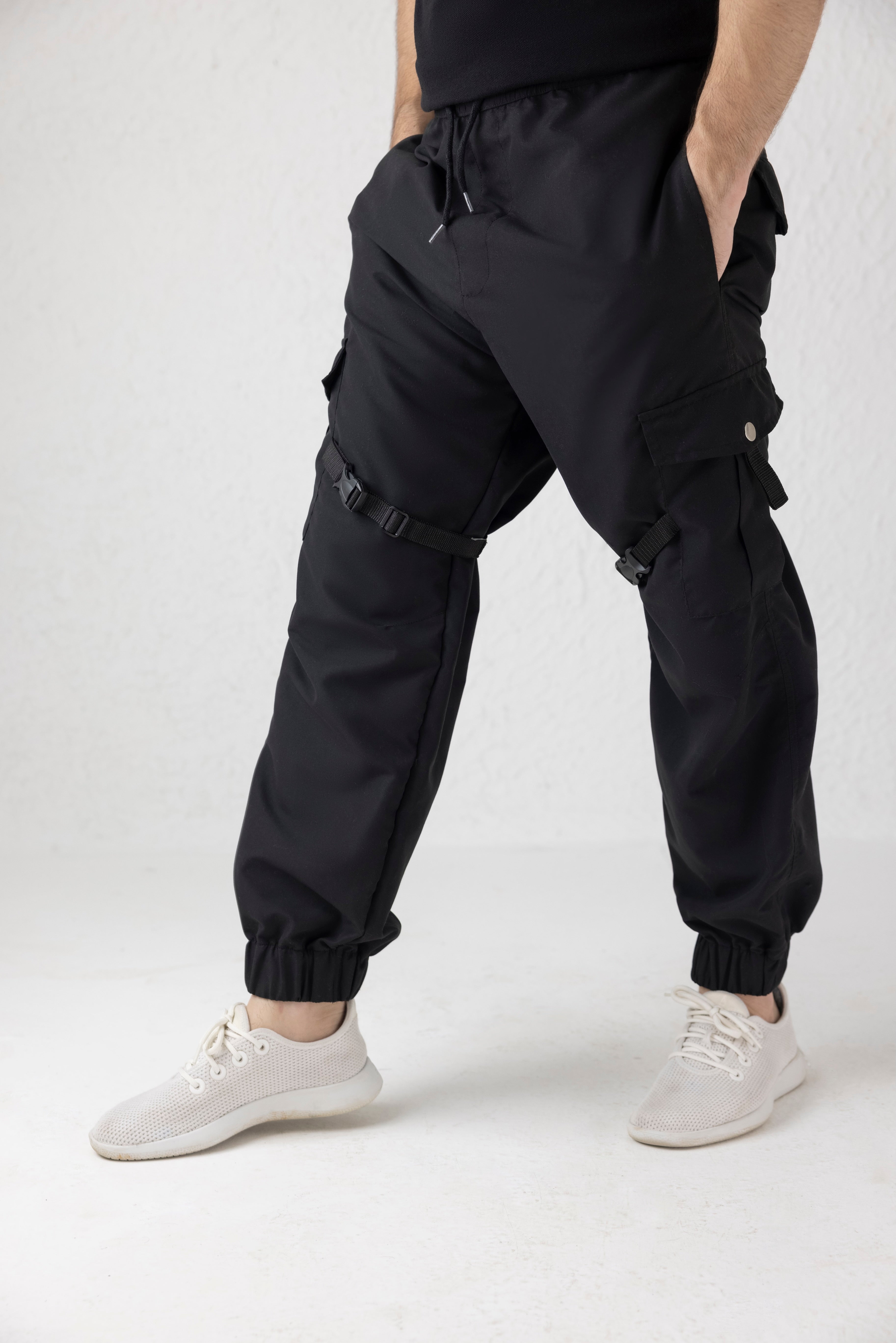 Side view showing adjustable thigh straps and tapered leg of black micro fabric cargo pants