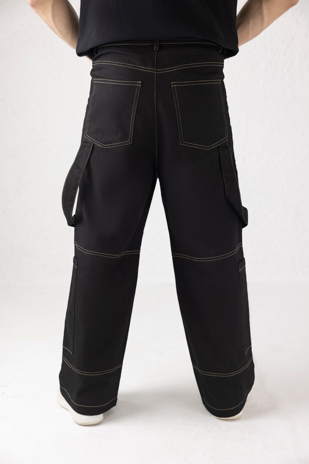 Back profile of black Onyxdrop denim cargo pants with contrast stitching and tapered fit