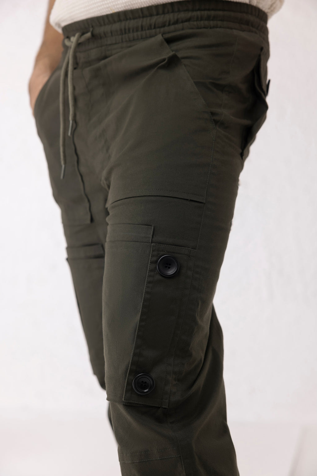 Close-up of black buttons and elastic hem on olive green twill cargo pants – Thyron by Decuir